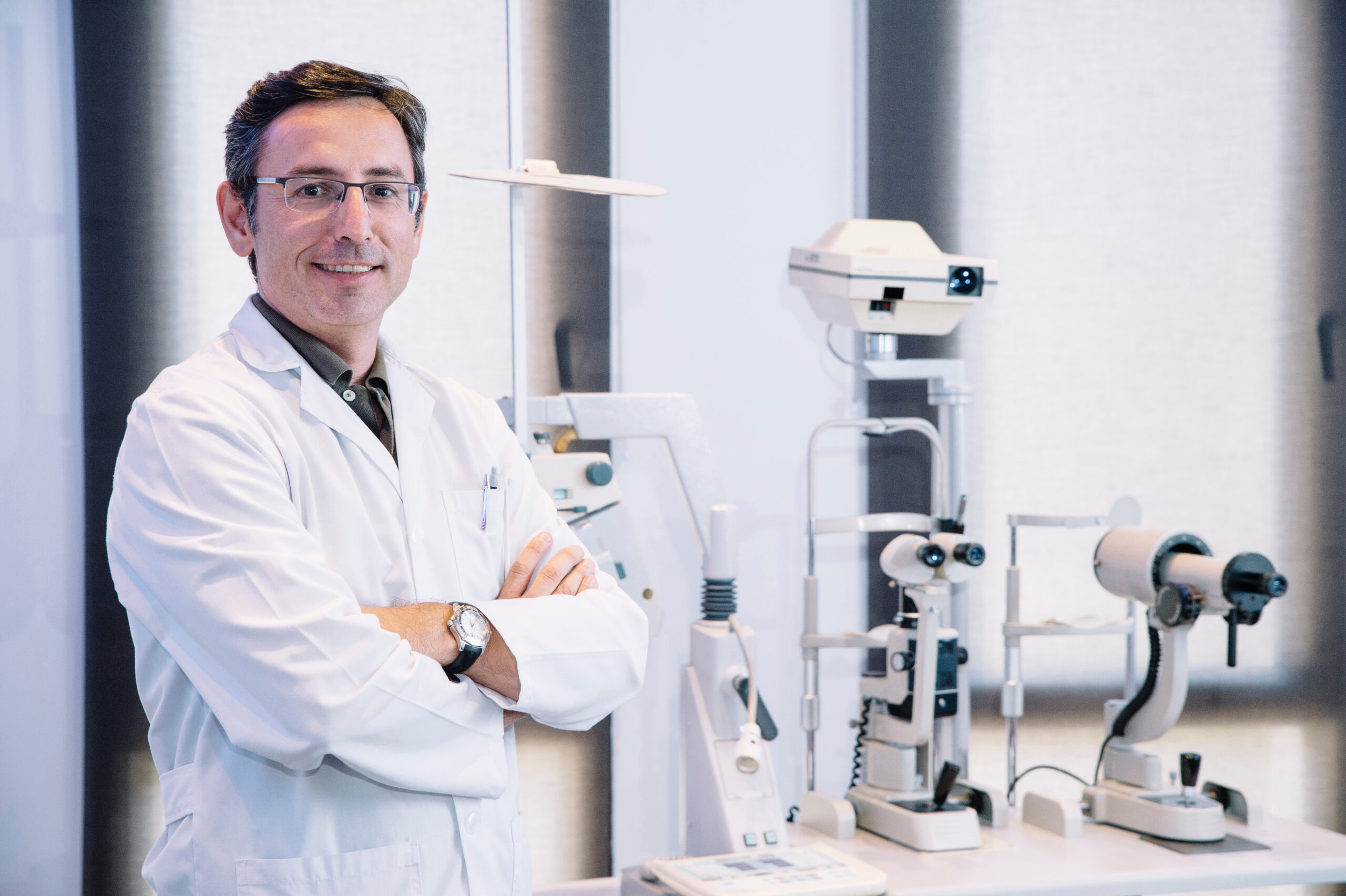 Augenarzt im Behandlungsraum neben Diagnosegeräten